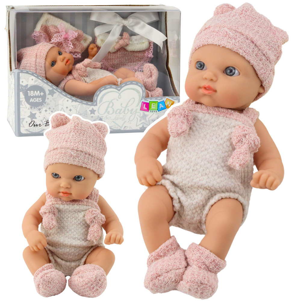 Bébibaba bézs-rózsaszín ruhában, sapkával és előkével, 18 cm